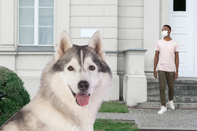 A man standing in front of a house with a dog