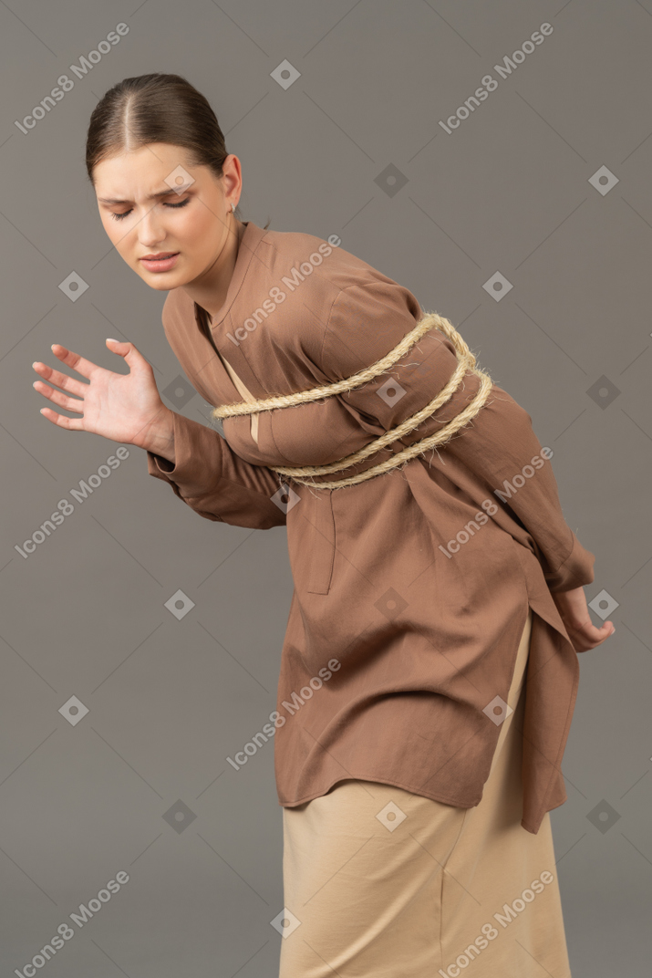 Young woman in ropes with free arm