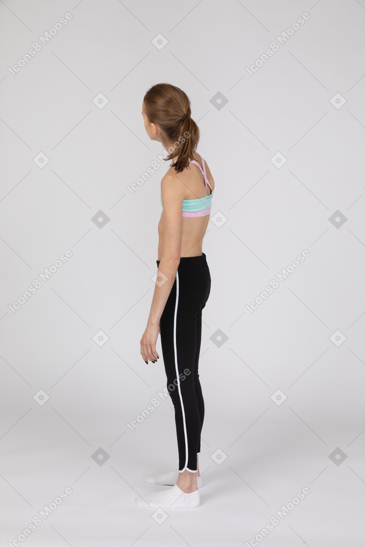 Vista lateral de uma adolescente em roupas esportivas olhando para o lado