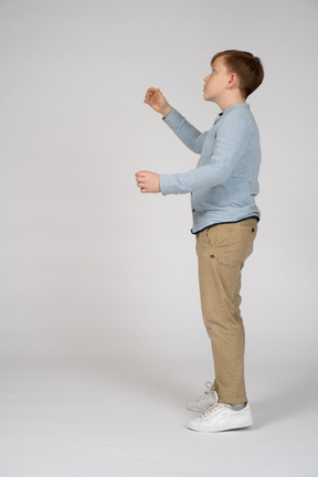 A young boy standing in a pose with his hands in the air