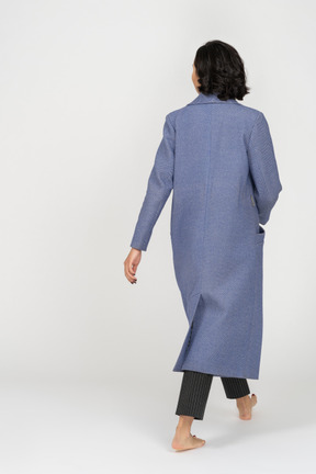 Back view of woman in coat walking barefoot