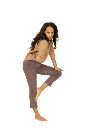 Side view of a confused dark-skinned young female leaning on her leg