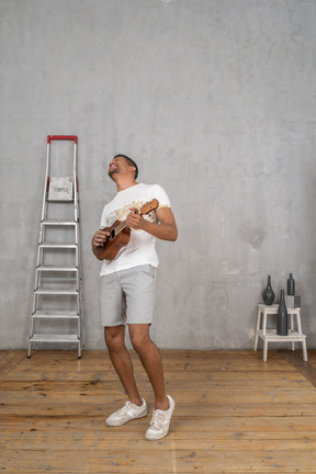 Visão de três quartos de um homem tocando ukulele e recostando-se alegremente