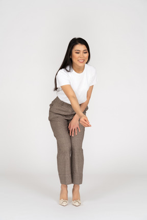 Front view of a young lady in breeches and t-shirt outstretching her hand and bending down