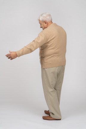 Vista lateral de un anciano con ropa informal de pie con los brazos extendidos