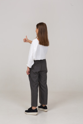 Three-quarter back view of a young lady in office clothing showing thumbs up