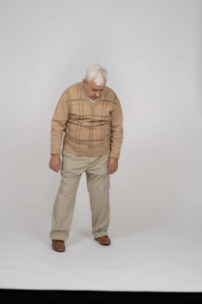 Front view of an old man in casual clothes looking down