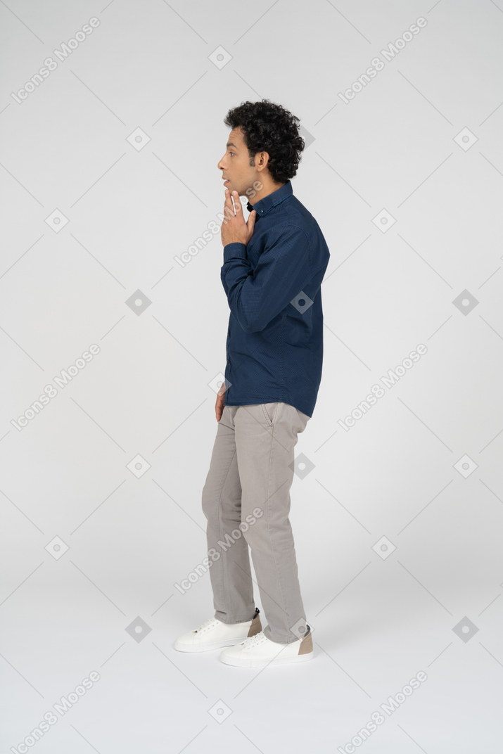 Side view of a man in casual clothes touching his mouth
