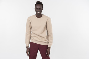 A young black man in a grey sweater standing alone on the white background