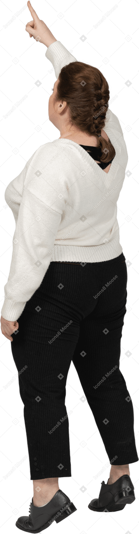 Rear view of a plus size woman in casual clothes standing with raised arm