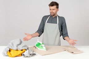 Young househusband looking outraged by all clothes to iron