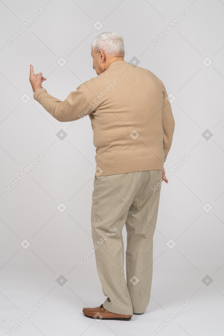 Retrovisione di un uomo anziano in abiti casual che punta verso l'alto con un dito