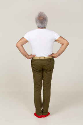 Back view of a man standing with hands on waist