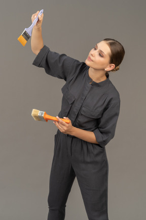 Woman in gray coveralls choosing a paint brush