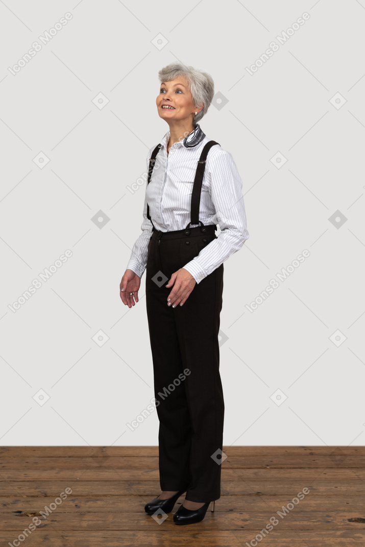 Vista de três quartos de uma mulher idosa esperançosa vestida com roupas de escritório