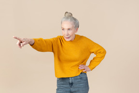 Elegante mujer mayor apuntando a algo