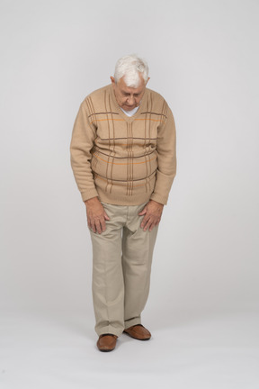 Vista frontale di un vecchio in abiti casual che guarda in basso