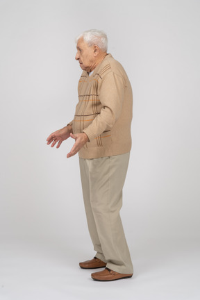 Vista lateral de un anciano con ropa informal de pie con los brazos extendidos