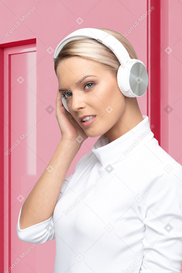 A woman in white headphones on a pink background