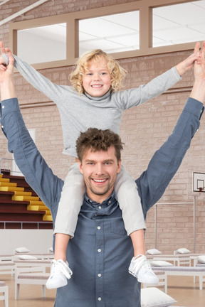 A man holding a little girl on his shoulders
