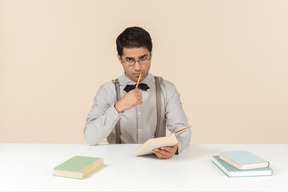 Jovem professor pensativo, lendo um livro