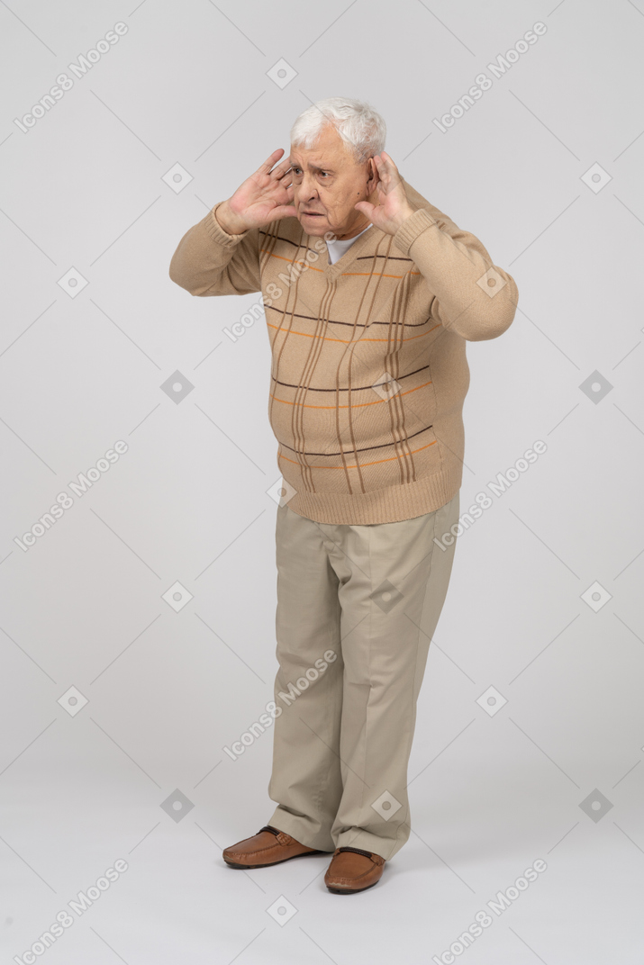 一位身着休闲服的老人的正面图握着靠近耳朵的手