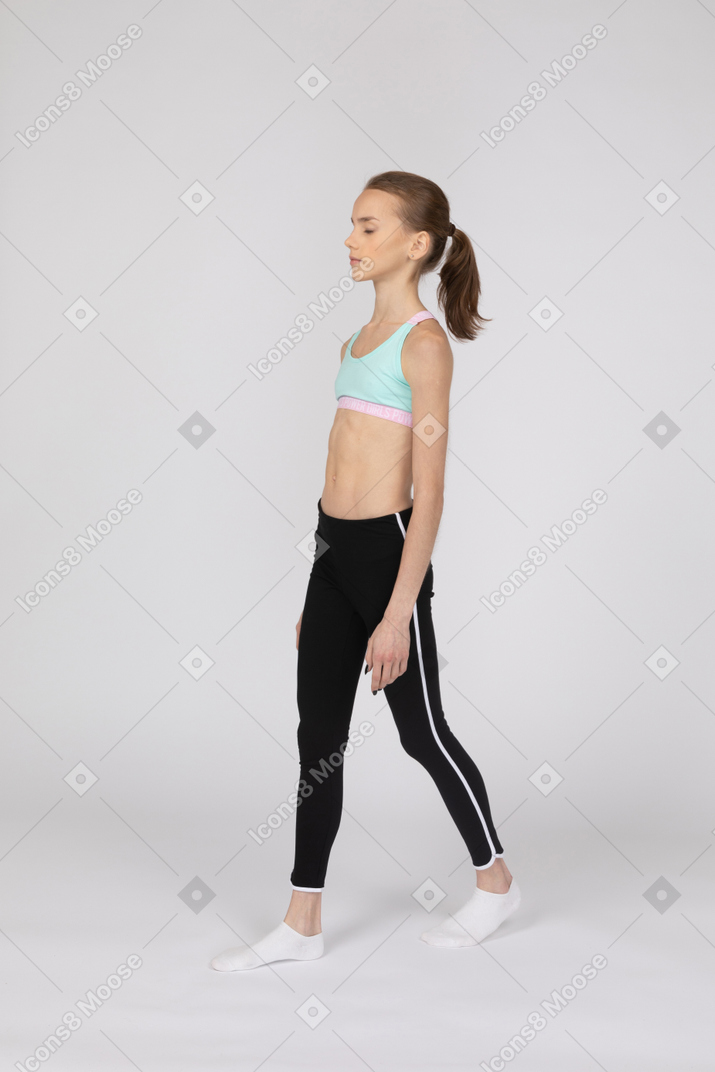 Vista di tre quarti di una ragazza adolescente in abiti sportivi a piedi