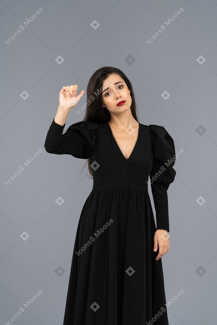 Front view of a miserable young lady raising her hand