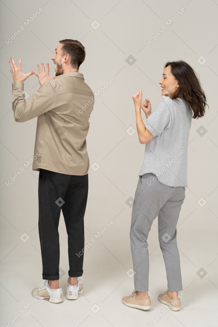 Three-quarter back view of young couple cheering
