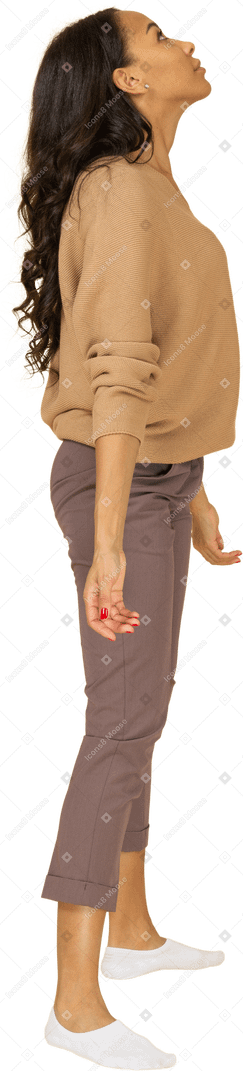 Vista lateral de uma jovem de pele escura em pé com os braços abertos