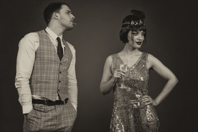 Gentleman standing next to a charming flapper holding a glass of champagne