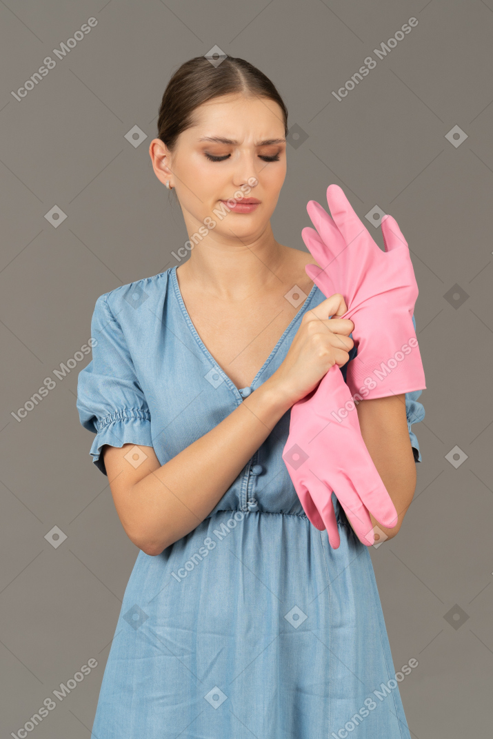 Portrait of a young woman looking irritated while taking off a latex glove