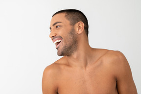 Barechested contented young man laughing