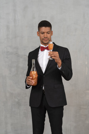 Vista frontal do homem com roupa formal, olhando para uma taça de champanhe