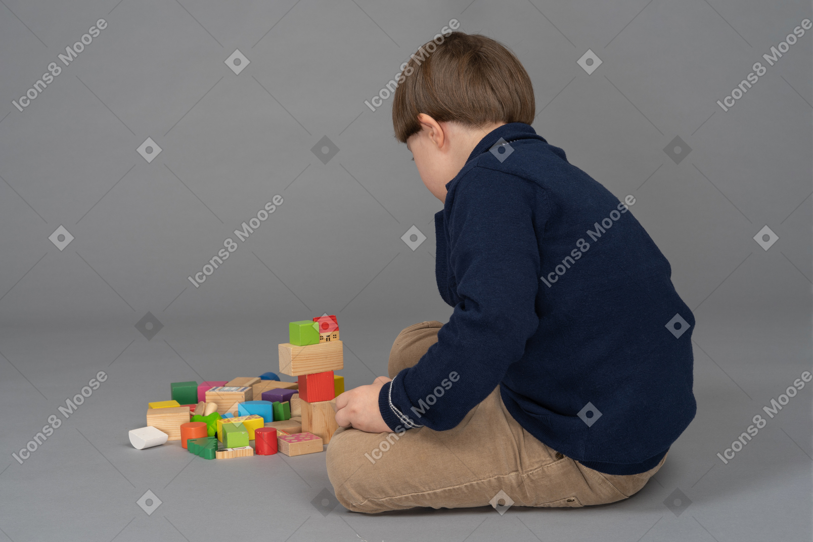 Back view of a little boy playing with building blocks