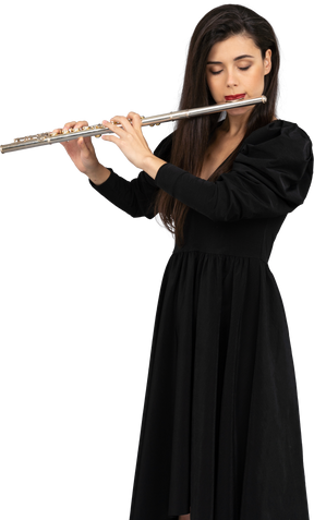Вид спереди серьезной молодой леди в черном платье, играющей на флейте
