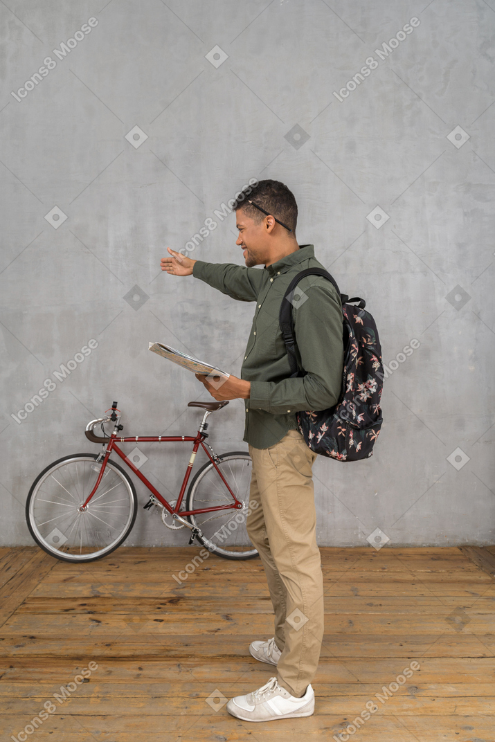 Seitenansicht eines mannes mit rucksack und einer karte mit wegbeschreibungen