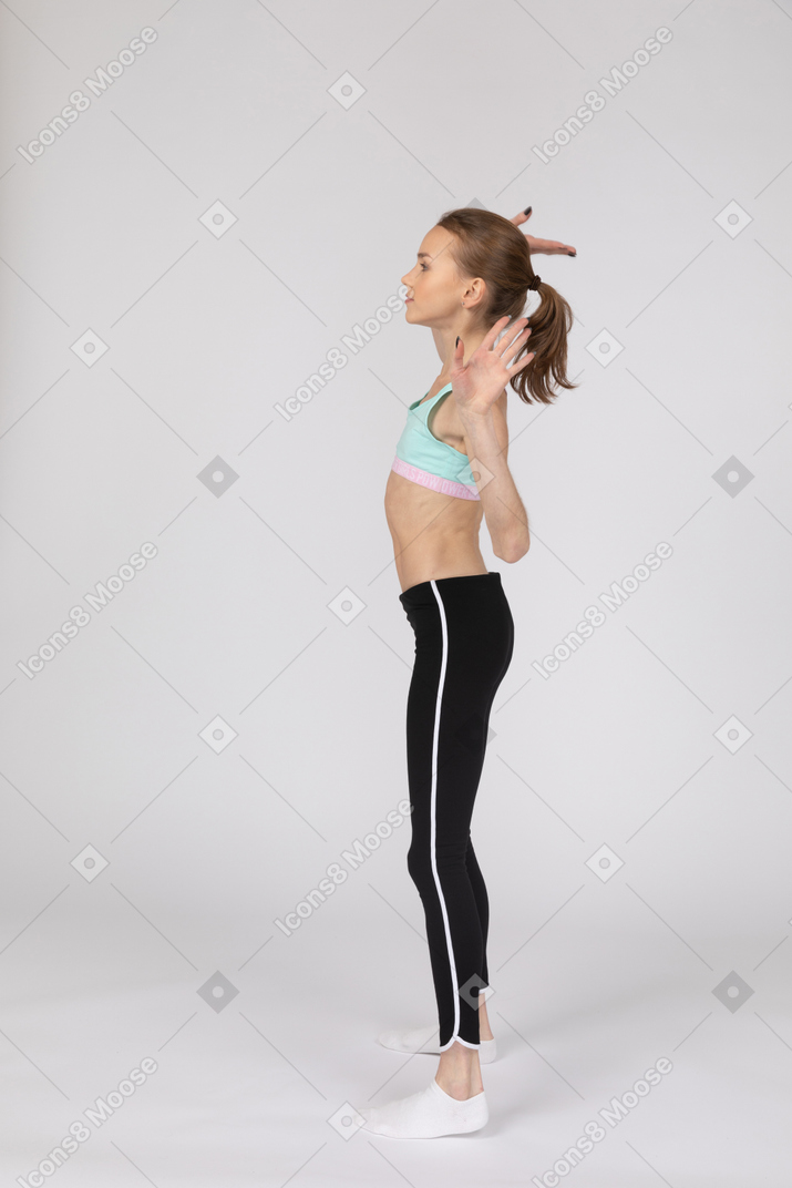 Side view of a teen girl in sportswear widely outspreading her hands