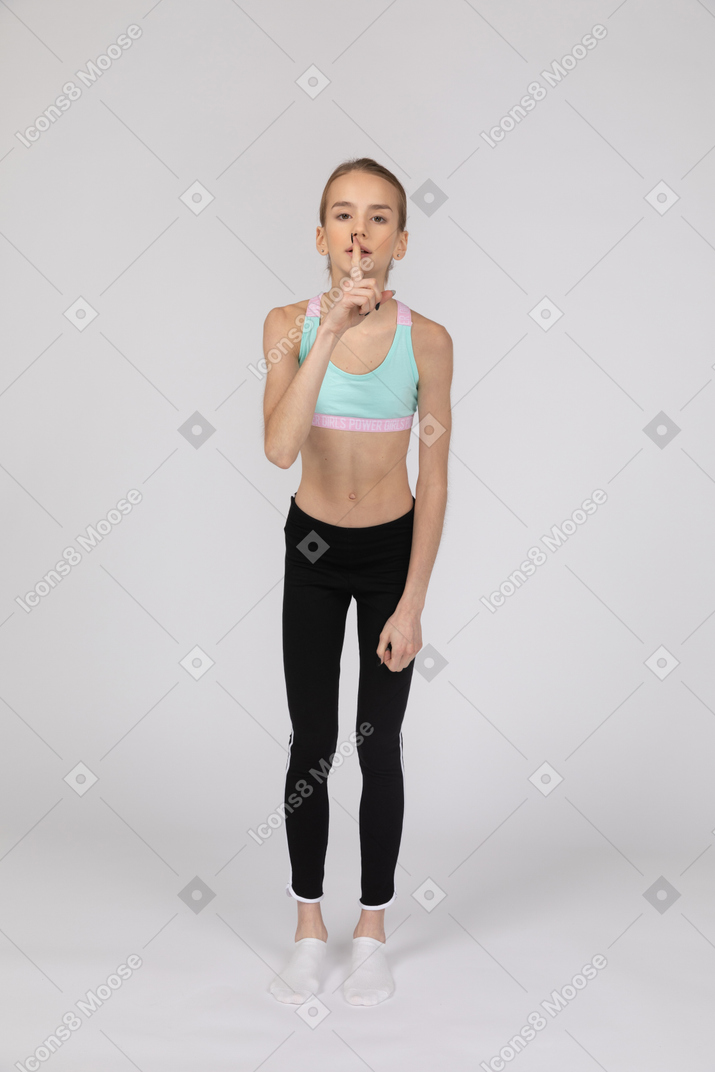 Menina adolescente em roupas esportivas fazendo gesto de silêncio