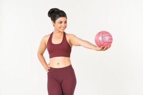 Jovem mulher indiana no sportswear segurando uma bola rosa