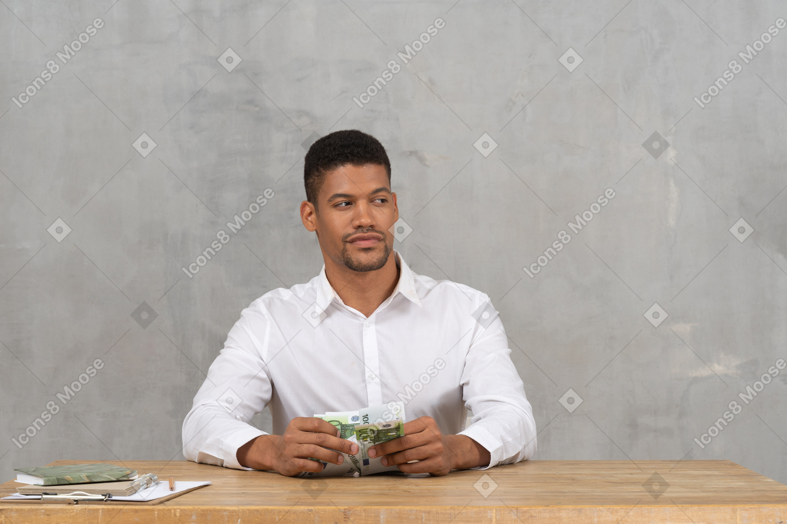 Молодой человек держит деньги и смотрит в сторону