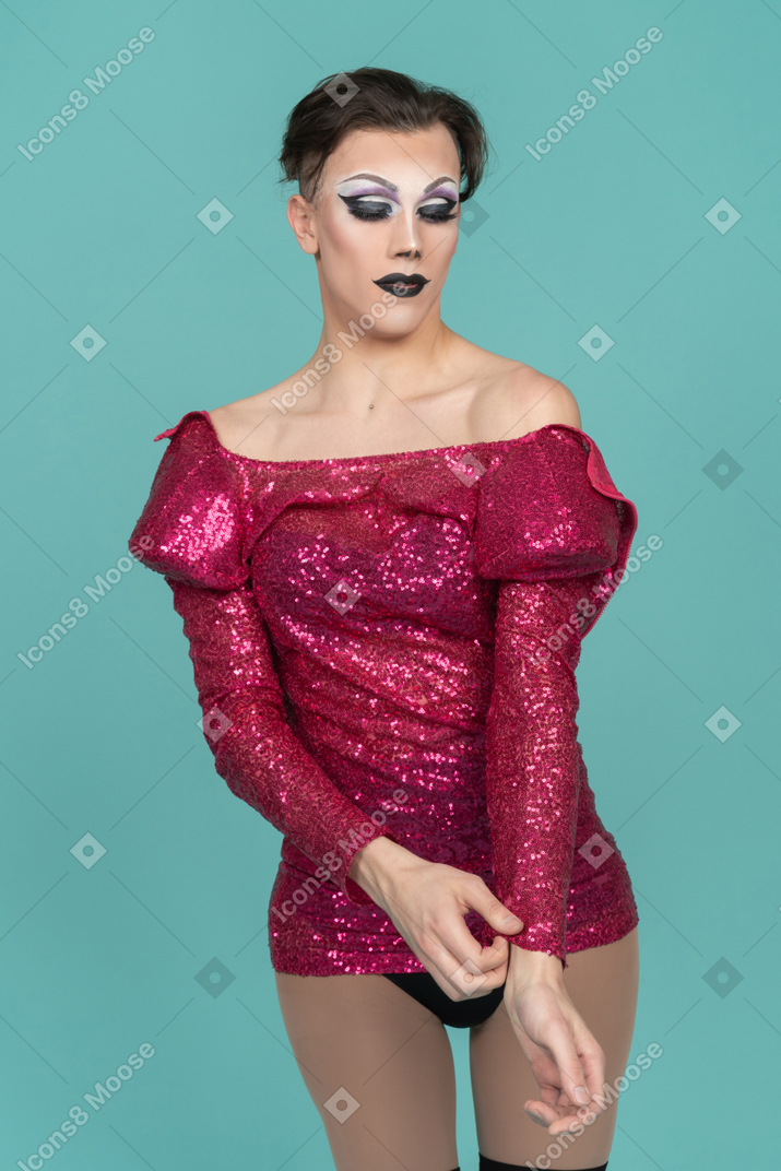 Drag queen in stage make-up taking off pink dress