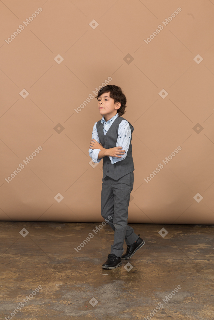 Vista frontal de um menino bonito de terno caminhando para a frente
