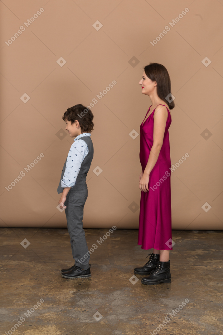 Mujer en vestido rojo y niño de pie en el perfil