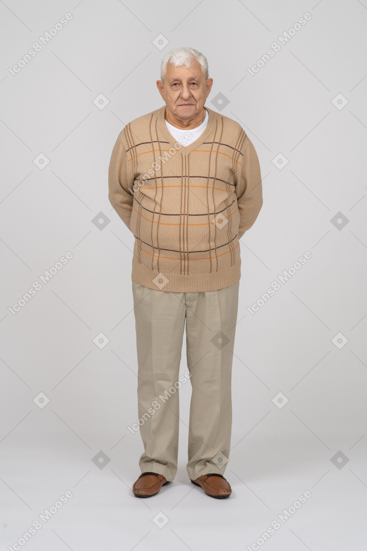 一位身穿休闲服的老人双手背在背后站着，看着相机的正面图