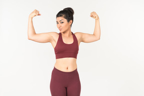 Femme indienne en vêtements de sport montrant les muscles