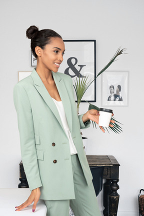 Black woman standing in office and holding coffee cup