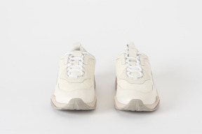 A front shot of a pair of white and beige sneakers