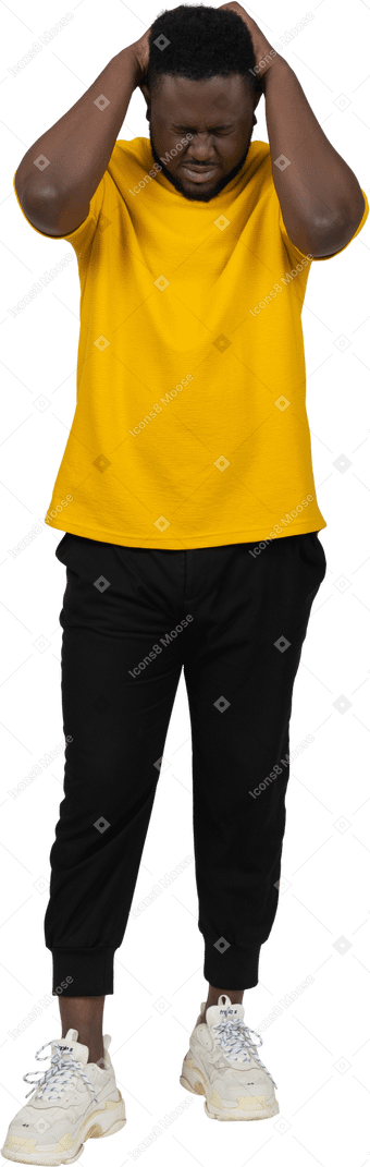 Vista frontale di un giovane uomo dalla pelle scura in maglietta gialla che tocca la testa