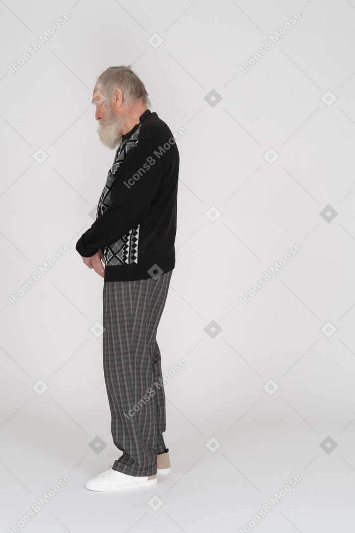 Side view of elderly man standing with clasped hands